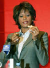 U.S. singer and actress Whitney Houston looks at a gift during a news conference in Shanghai July 21, 2004. Houston will give a concert in Shanghai on Thursday as part of her China tour. 